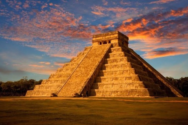 a tall clock tower with Chichen Itza in the background